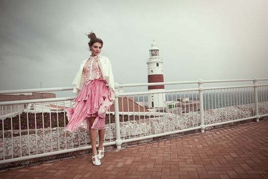 A woman wearing a pink skirt and white blouse, designed by Gabriella Sardena